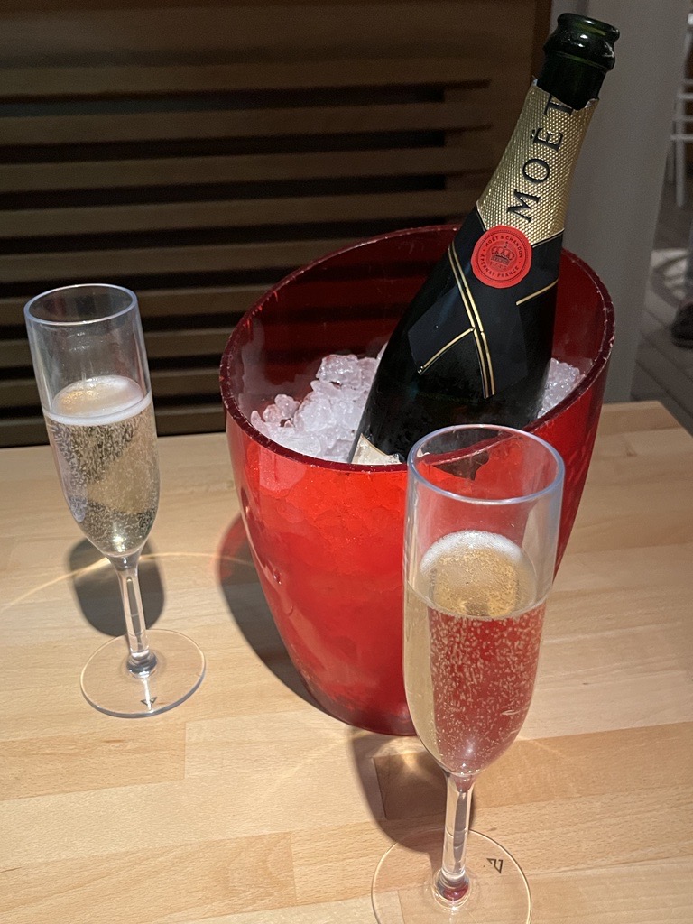 Moet Champagne in red bucket with ice and two champagne flutes filled with champagne